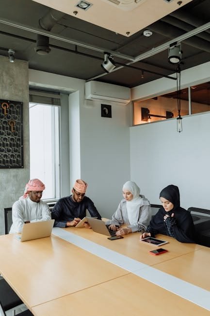 A group of Muslim professionals collaborating in a modern meeting room with laptops and tablets.
