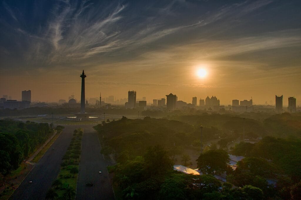 A breathtaking aerial view of Jakarta's skyline at sunset, highlighting the iconic National Monument.
