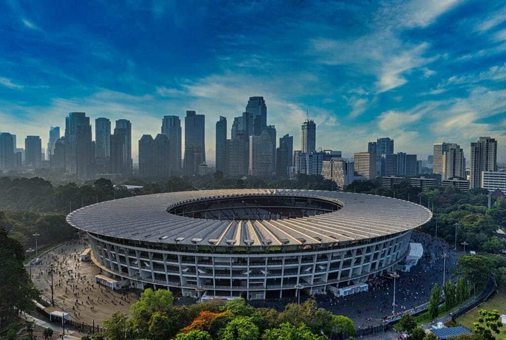 Stunning aerial view of Gelora Bung Karno Stadium with Jakarta skyline in the background.